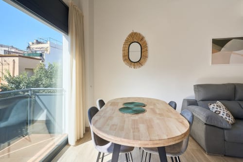 Comedor luminoso y moderno en apartamento Tr3sor Homes Calella con mesa de madera, sillas grises y vista al balcón