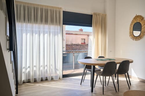 Comedor moderno con mesa de madera y sillas negras con vistas a los tejadillos de Calella, apartamento Tr3sor 33