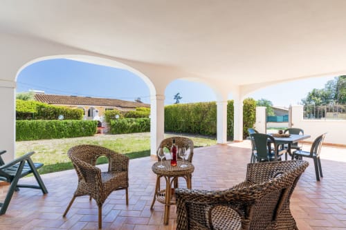 Terrazza coperta con sedute in vimini dell'hotel YouInSardinia a Bari Sardo, Italia con vista sul giardino