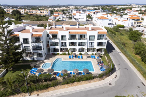 Hotel RB Algarve em Albufeira, Portugal com apartamentos brancos, telhados laranja e piscina azul brilhante rodeada por