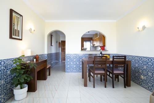 Sala de jantar de apartamento hoteleiro moderno com azulejos portugueses azuis e brancos, móveis de madeira e arcadas no RB Algarve