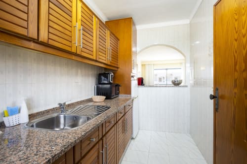 Cozinha moderna com armários em madeira, bancada em granito e pia em aço inox no apartamento RB Algarve ANA, Albufeira
