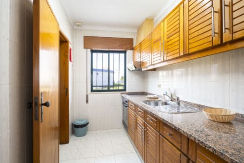 Cozinha moderna no apartamento RB Algarve com armários de madeira, bancadas em granito e janela com vista para a piscina