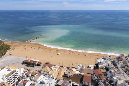 Vista aérea da praia de Albufeira com areia dourada, águas turquesas e edifícios à beira-mar do hotel RB Algarve