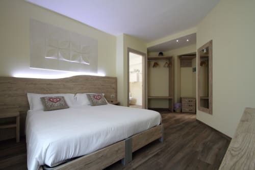 Modern bedroom at Il Viottolo in Roccaraso with queen bed, wooden headboard, illuminated closets, and contemporary