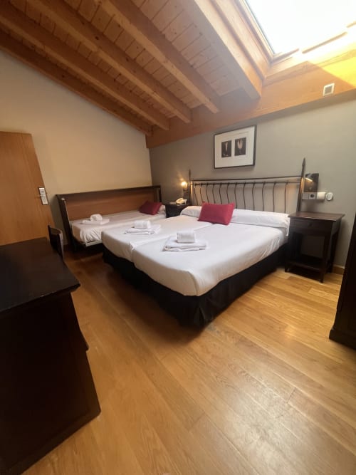 Gran habitación triple en CasaAzcona con vigas vistas, dos camas, vistas a la montaña y suelo de madera