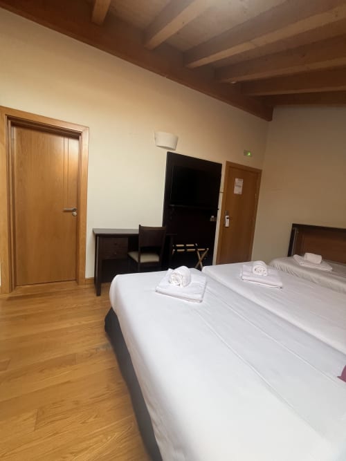 Dreibettzimmer im Casa Hotel mit Bergblick, ausgestattet mit Betten in weißer Bettwäsche, Holzböden, TV und modernen Annehmlichkeiten