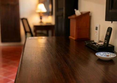 Mesa de hotel con superficie de madera oscura, lámpara, controles remotos y cuenco decorativo en la habitación moderna de Villa