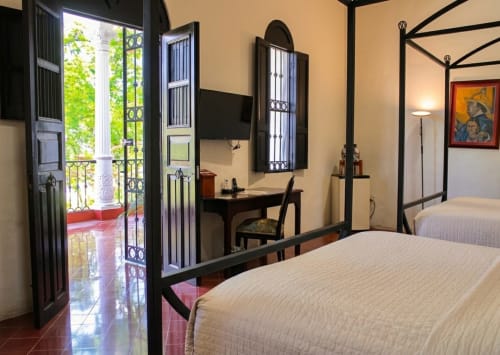 Suite colonial del hotel boutique Villa del Carmen con acceso a terraza, mobiliario de hierro forjado y comodidades modernas