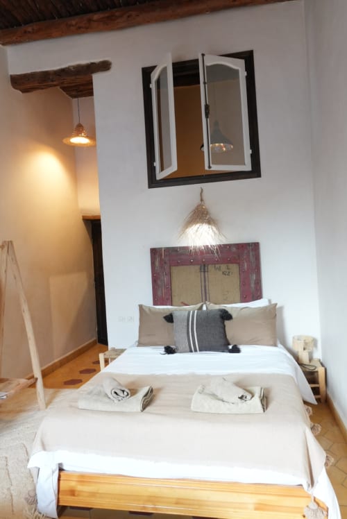 Suite moderne d'hôtel avec lits jumeaux, poutres bois, miroir au-dessus de la tête de lit rouge, luminaire suspendu et vue sur la piscine au Rwanda