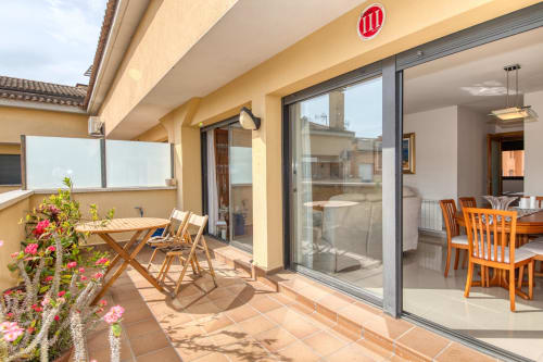 Modern penthouse terrace at Garcia property with dining area, lounge chairs, flowering plants, and expansive views in