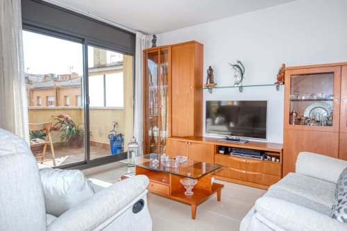 Modern living room at Garcia Hotel with orange wood furniture, white sofas, TV, and balcony overlooking in Costa brava, Spain