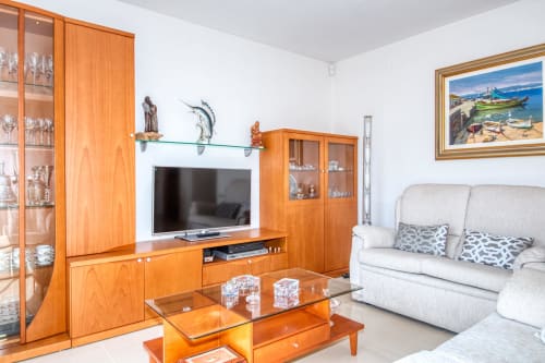 Modern living room with wooden furniture, TV, white sofa, and decorative shelving at Garcia property in Spain
