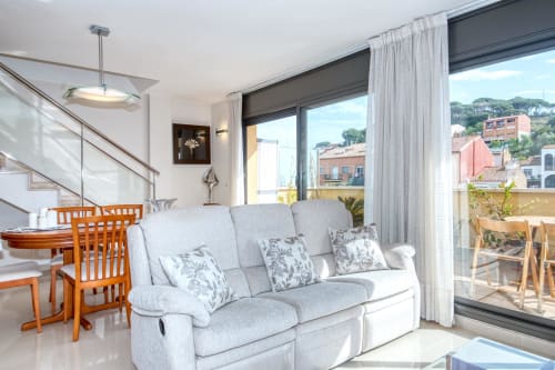 Modern living room with light gray sofa, wooden chairs, and sea view at luxury property in coastal Spain