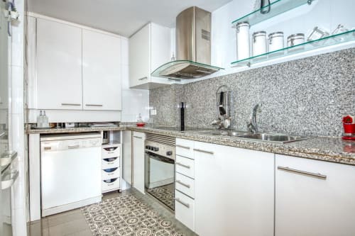 Modern white kitchen with granite countertop, stainless steel appliances and mosaic backsplash at Hotel García-al-Mar