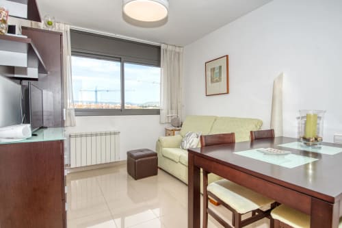 Modern apartment living room at Garcia Hotel with cream sofa, wooden furniture, and city views in vibrant, contemporary
