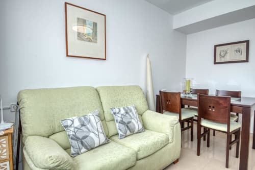 Light green sofa with patterned pillows in modern living area at Garcia Garcia hotel with dining furniture and framed artwork