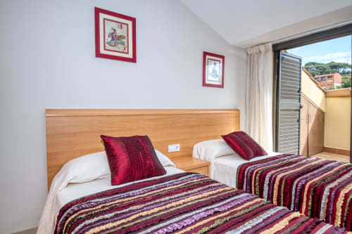 Twin bedroom at Hotel with striped blankets, wooden headboard, red pillows and balcony view in bedroom