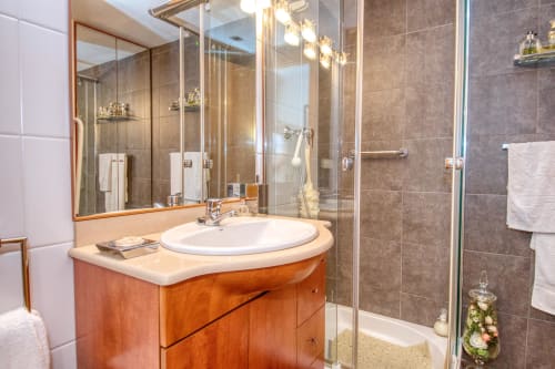 Modern bathroom with wooden vanity, round sink, and glass shower enclosure at Hotel Garcia property