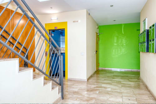 Modern hotel corridor at Garcia-rich with vibrant green wall, orange staircase, and wooden flooring in Spain