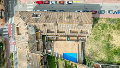 Arial view of Garcia Garcia hotel with tiled roofing, courtyard, parked cars, and green spaces in