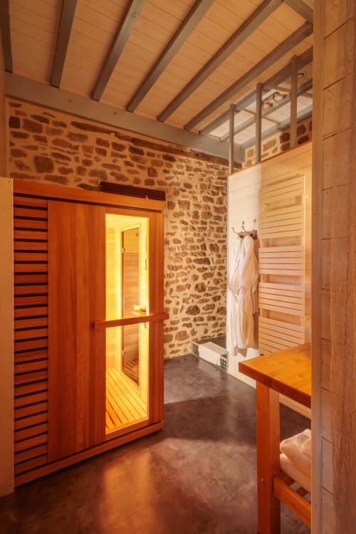 Le sauna et spa moderne de Les InstantsVolés en France, avec intérieur en bois et murs en pierre