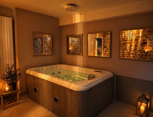 Le spa aux murs de pierre du boutique-hôtel Les instants volés : bain à remous aux eaux teintées de verdure, ambiance chaleureuse, miroirs et chandelles