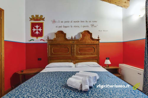 Camera tripla in Villa hotel con letto in legno, pareti rosse, biancheria bianca e vista sul giardino in Italia