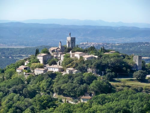 Medieval village La-garde-adhémar perched on hilltop surrounded by lush green landscapes and distant mountains