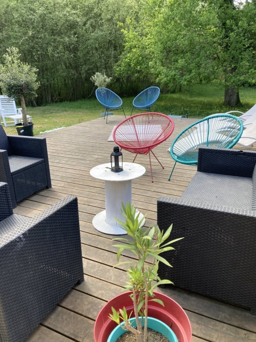 La terrasse des mésangères avec ses chaises colorées, plantes en pot et vue sur les jardins à chaumont-sur-tharonne