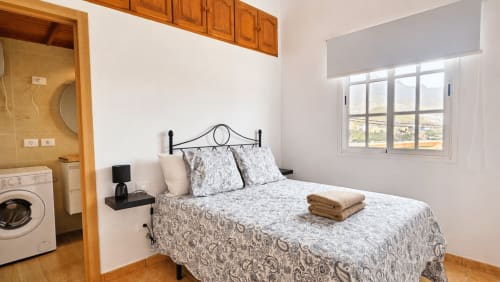La aldea villa: dormitorio moderno con ropa de cama estampada, ventana con vista a montañas, lavadora y baño privado