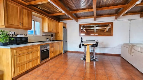 Villa moderna con cocina y salón, vigas de madera, azulejos de terracota y electrodomésticos de acero inoxidable en La aldea