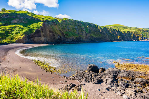 Scenic coastal beach cove with turquoise waters and lush green cliffs near Golden Mermaid Villa in Ribeirinha, Portugal