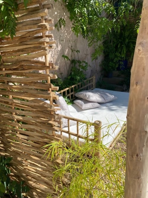 Outdoor bed nook at Le Patio aux Oiseaux in La Ciotat, surrounded by lush greenery and wooden screening