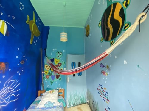 Aqualove room at Le Lama Zébré with underwater-themed mural, sea creatures, colorful fish paintings, and red slide in