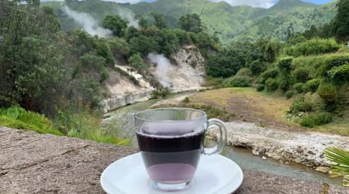 Café escuro em xícara branca com vista para vale geotérmico na Villa Golden Mermaid, Ribeirinha Portugal