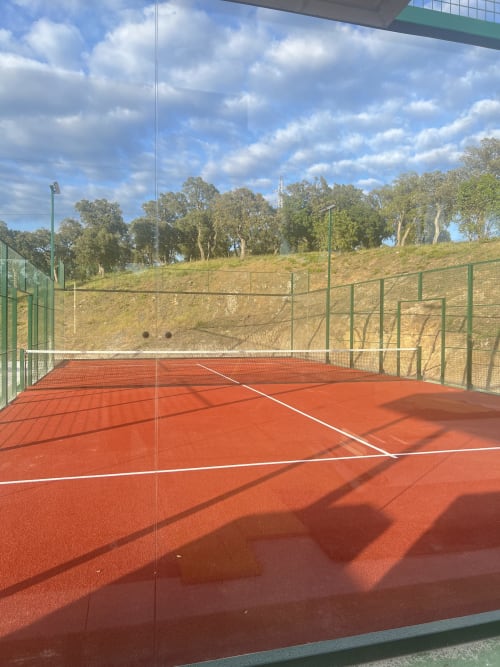 Red clay tennis court with green fencing at Villa Nais, Bormes-les-Mimosas, overlooking countryside
