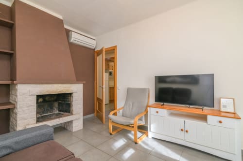 Modern apartment living room at Rural Montseny with fireplace, TV, wooden furniture, and AC in Gualba