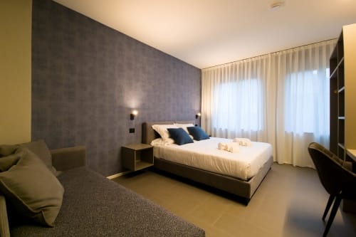Camera da letto moderna al SMalL Guesthouse di Bussolengo con letto, parete in accento scuro e luce naturale dalle finestre
