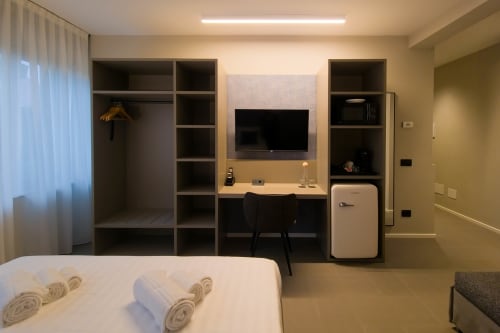 Camera moderna presso SMalL Guesthouse a Bussolengo con letto, scrivania, TV, scaffali e frigorifero retrò