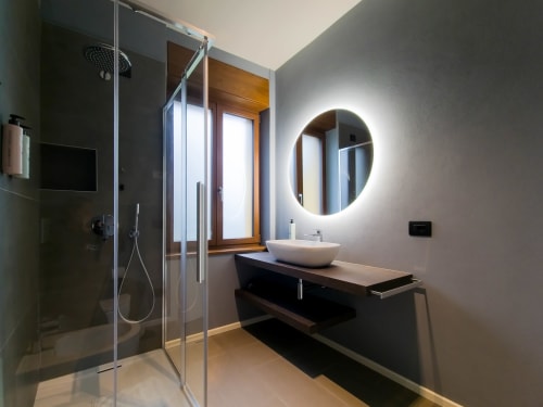 Bagno moderno nella camera Sodalite di SMalL Guesthouse, Bussolengo con specchio illuminato, lavabo in ceramica e doccia in vetro