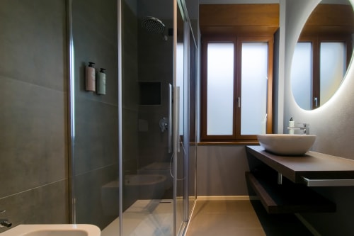 Bagno moderno nella camera Sodalite dello SMalL Guesthouse Bussolengo con doccia walk-in, lavabo a cascata e specchio illuminato