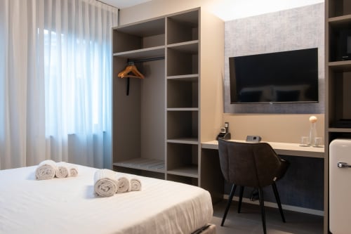 Camera Sodalite presso SMalL Guesthouse a Bussolengo con letto, cabina armadio, scrivania e TV