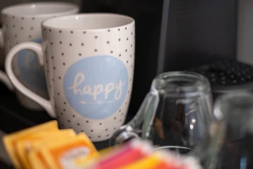 Tazza bianca a pois con scritta 'happy' nella camera Sodalite dello SMalL Guesthouse, Bussolengo