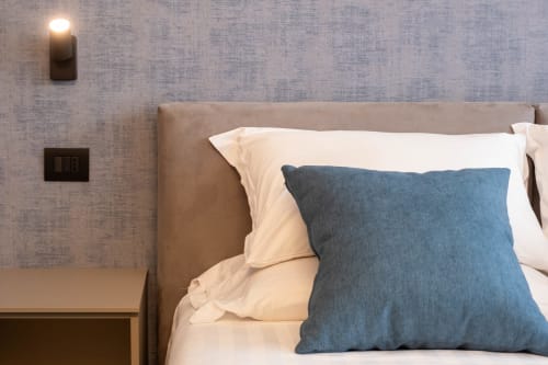 Camera moderna presso SMalL Guesthouse a Bussolengo con cuscino blu, biancheria color crema e applique murale