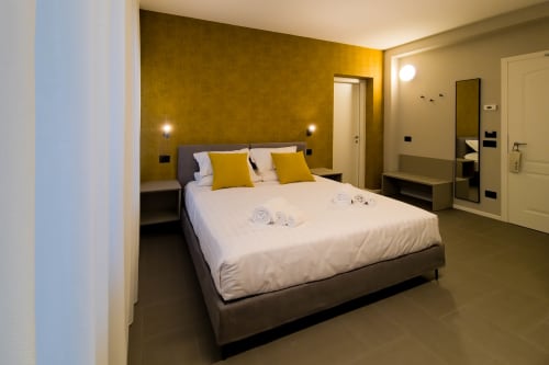 Camera Ambra presso SMalL Guesthouse a Bussolengo con letto king size, parete accento in senape e bagno en suite moderno