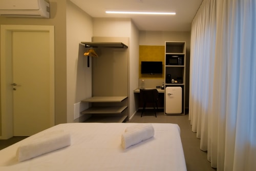 Camera Ambra presso SMalL Guesthouse a Bussolengo con letto, armadio, scrivania, frigorifero e area di lavoro