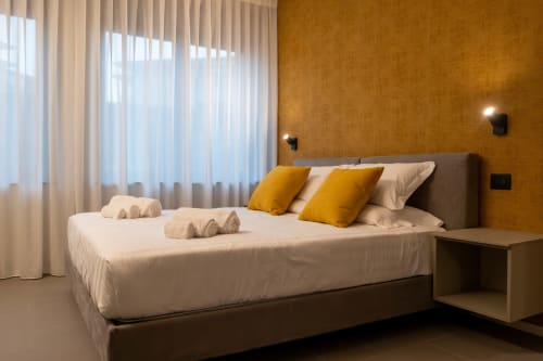 Camera Ambra presso SMalL Guesthouse a Bussolengo con letto moderno, cuscini gialli e parete color ocra