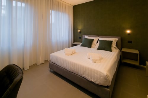 Camera Malachite presso SMalL Guesthouse a Bussolengo con letto queen, parete di accento verde e tende trasparenti