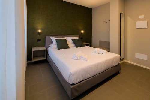 Camera Malachite presso SMalL Guesthouse a Bussolengo, Italia - camera da letto moderna con parete verde, letto queen e asciugamani bianchi